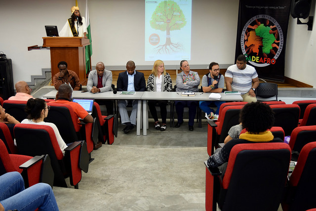 En la mesa central de un audiorio lleno se ven varios directivos y profesores y académicos afrodescendientes