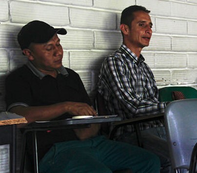 dos hombres (indígena e invidente) participando de taller en aula de clase.