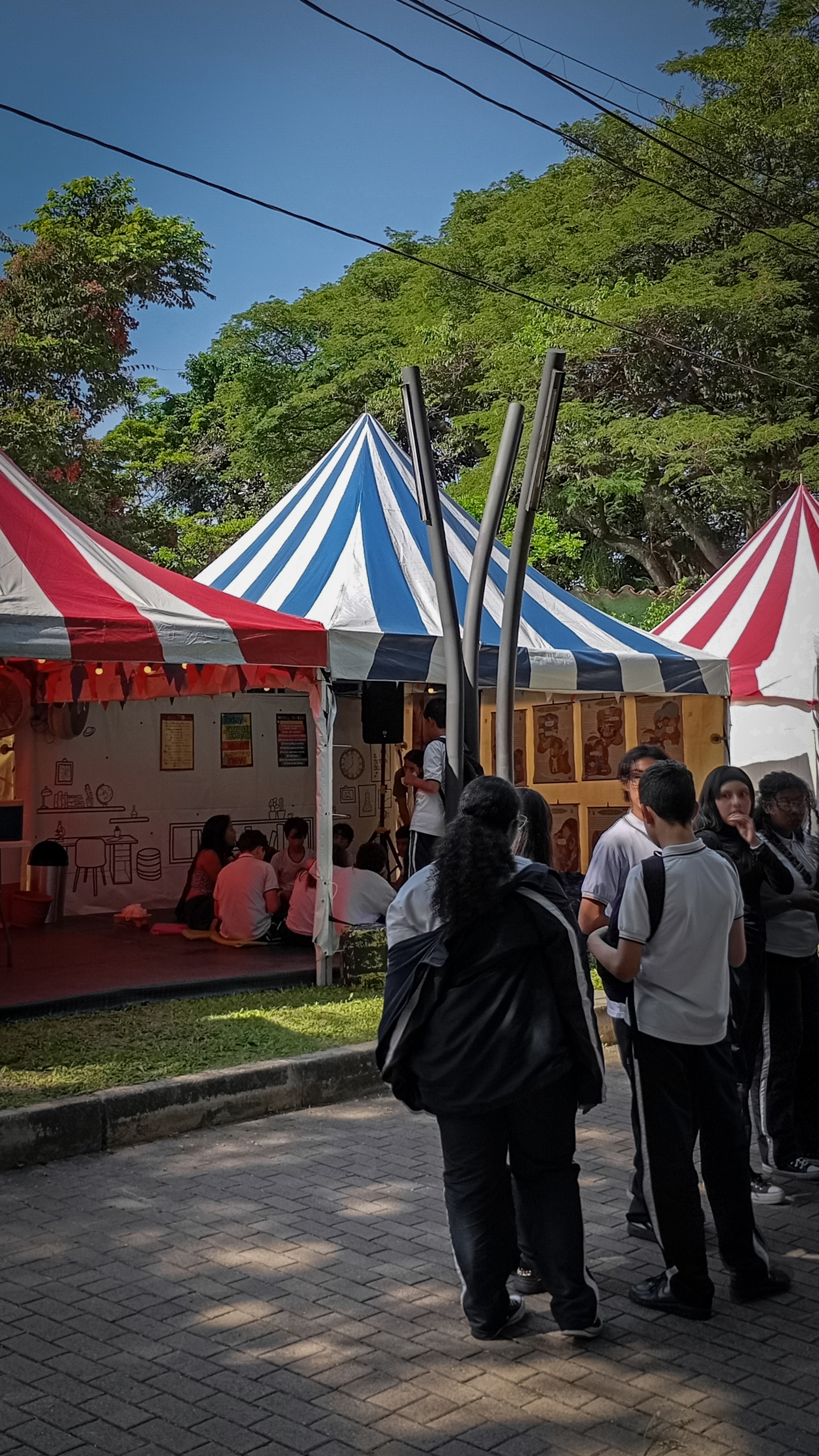 Estudiantes con uniforme de colegio de pie fuera de una carpa