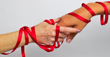 Dos manos entrelazadas con un hilo rojo rodeándola