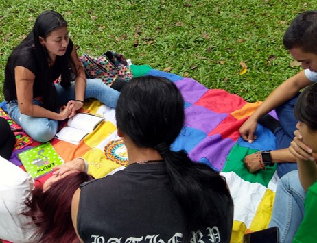 jóvenes indígenas sentados en el suelo, conversando.
