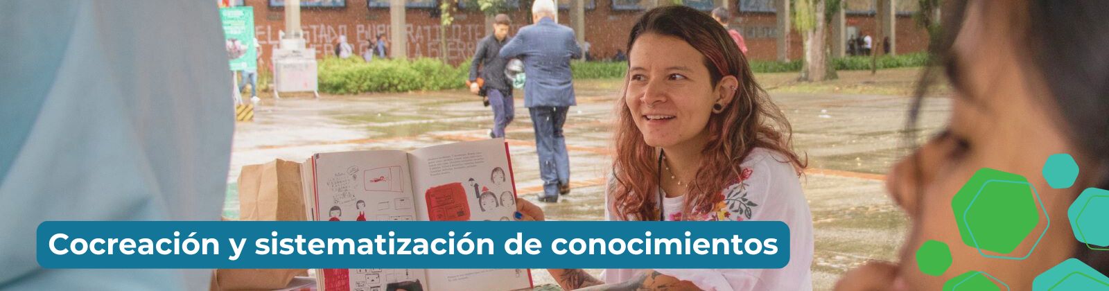 Descripción de imagen: En un espacio abierto se ve una mujer sosteniendo un libro que es observado por otras dos personas en actitud de escucha. En texto dice Cocreación y sistematización de conocimiento.