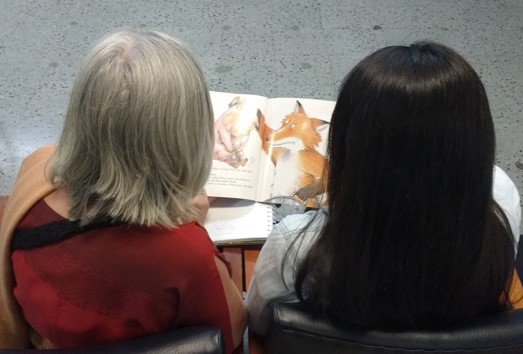 estudiante y profesora leyendo un cuento infantil.