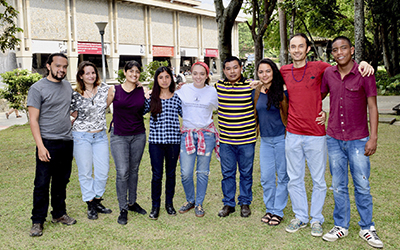 9 estudiantes de yepamasha están abrazados sonrientes, la biblioteca central se ve de fondo