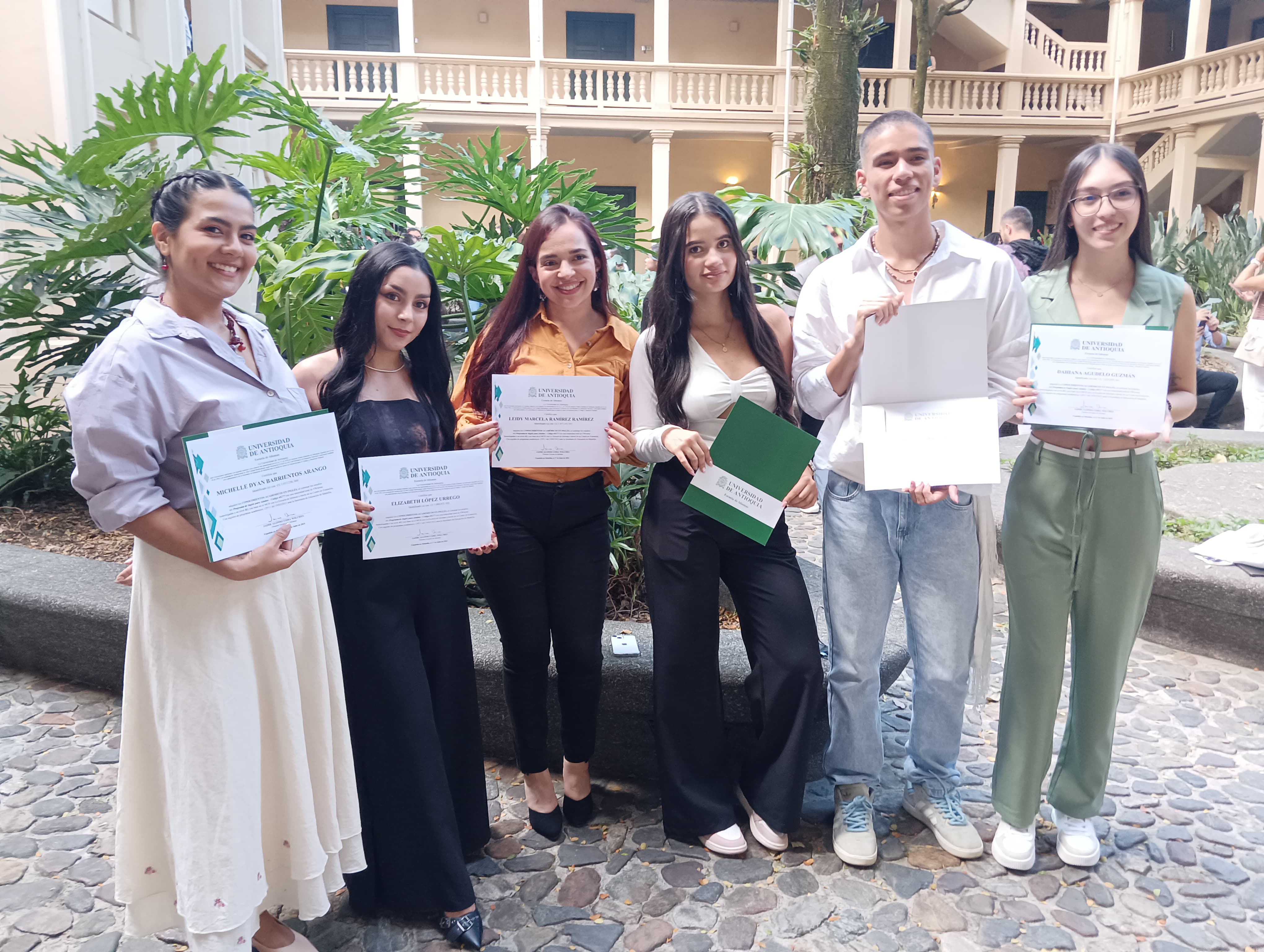 Estudiantes de pie con diplomas en las manos