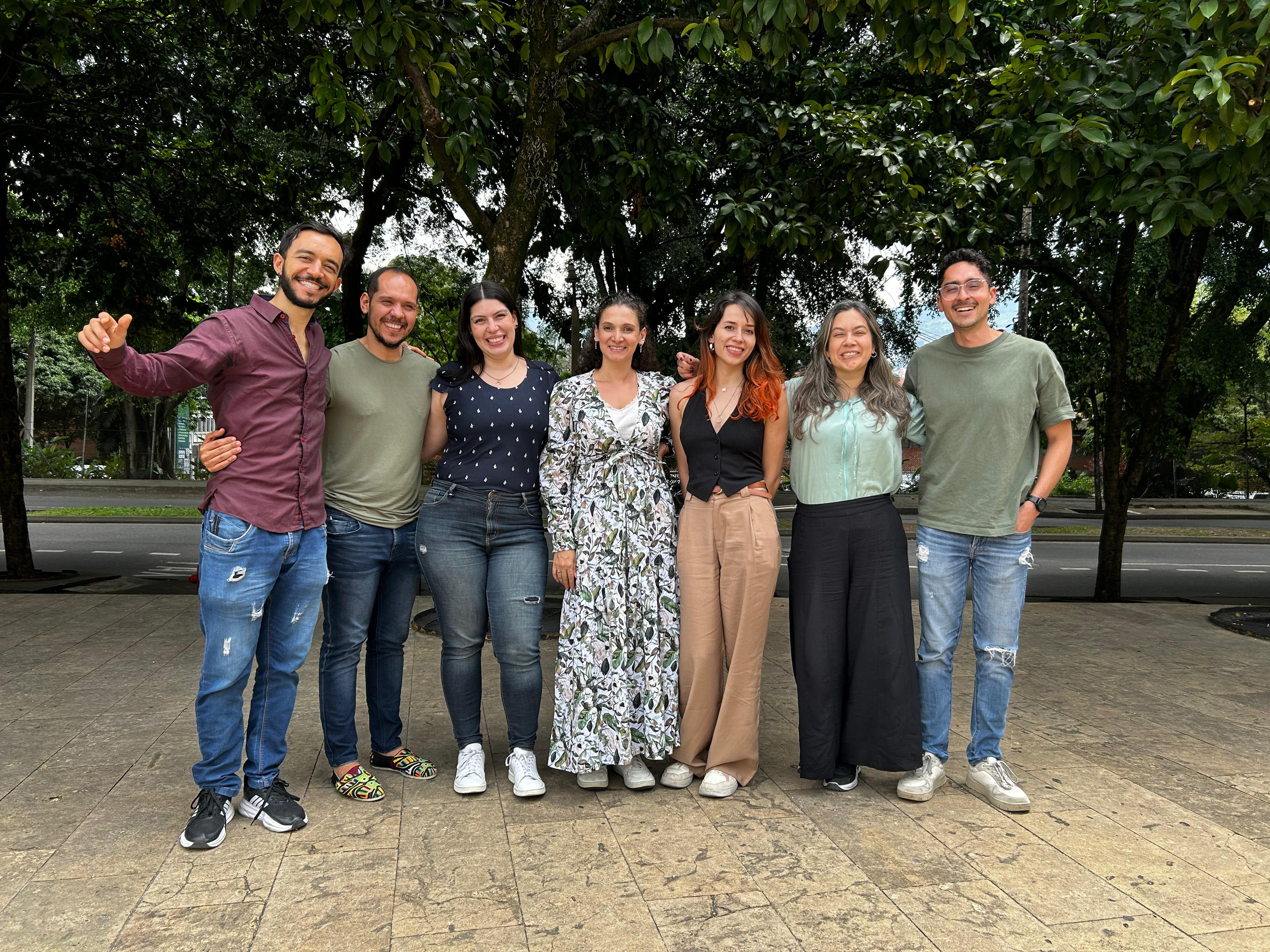 Siete personas de pie de fondo unos árboles