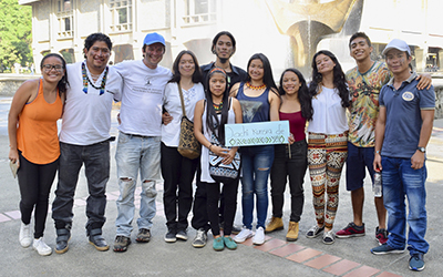 Aparecen 11 estudantes abrazados y  sonrientes mientras la profesora del curso sostiene un cartel que dice ebera chami