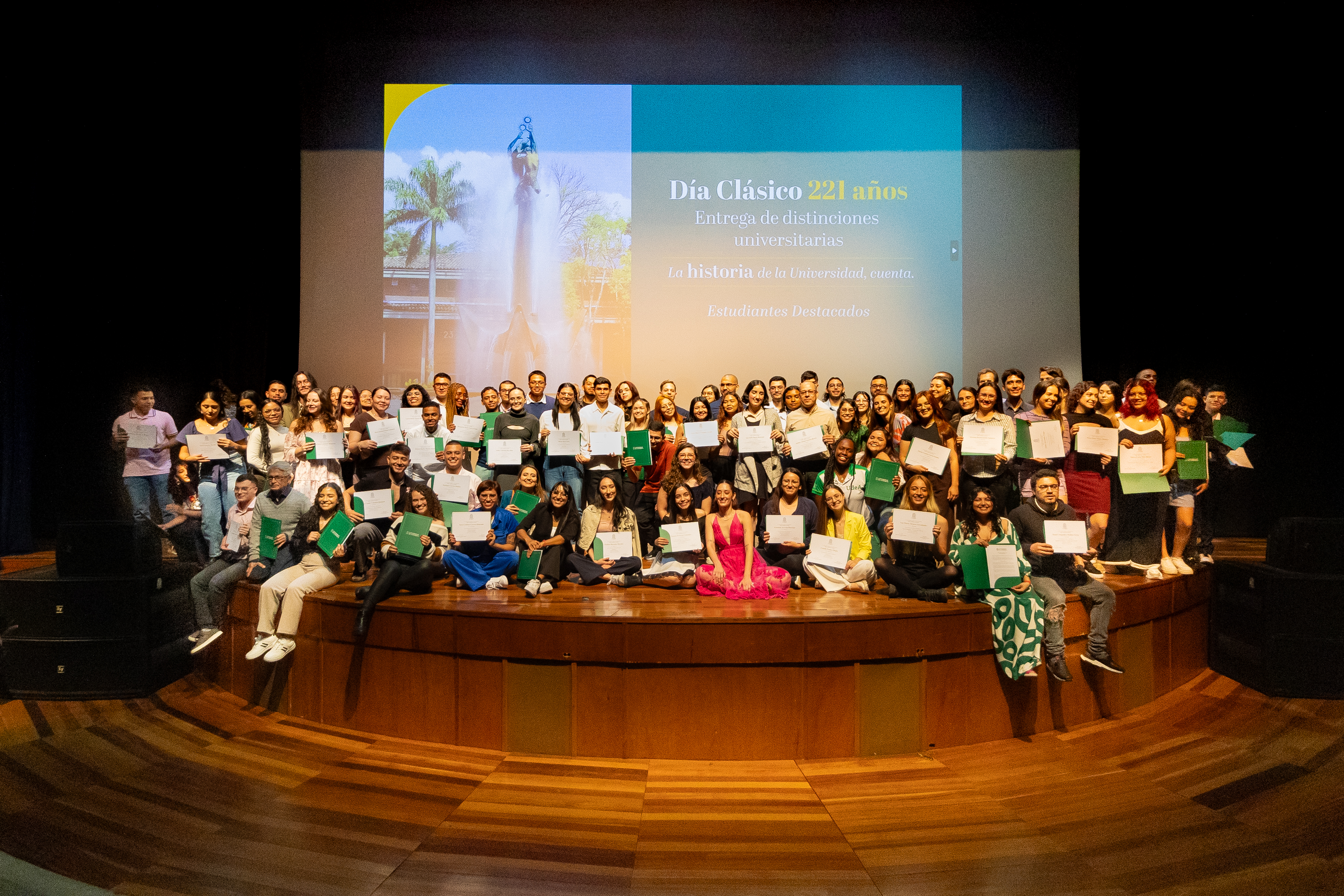 Estudiantes con diplomas de reconocimiento sobre el escenario del teatro Camilo Torres