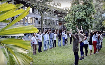 30 estudiantes en dos filas mirando y al cielo con los brazos arriba.