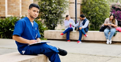 En primer plano, un estudiante de Atención Prehospitalaria observando un ejercicio de simulacro de evacuación en el campus El Carmen de Viboral